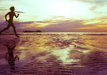 Healthy and mindful woman running on the beach.