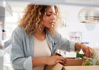 Woman carefully unpacks home food delivery