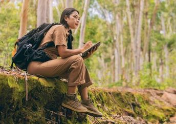 A biologist researches and records information discovered in the forest.