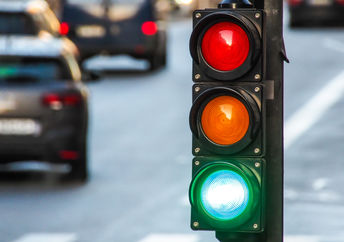 A traffic light, pedestrian crossing, and cars at a busy intersection.