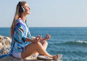 A woman meditates to the relaxing soundwaves of binaural beats.