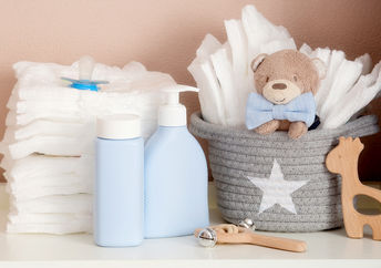 A stack of diapers, toys and baby accessories on a changing table.