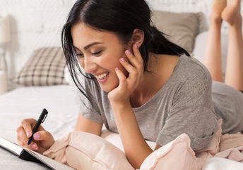 Young woman relaxing with a notebook and pen in her hands.