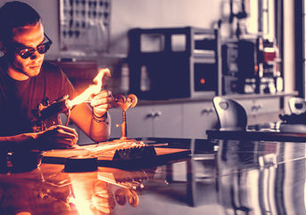 Glassblowing professional working on a torch flame with glass tubes.