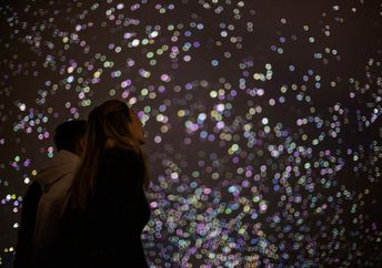 A woman watches silent, organic fireworks in the sky.