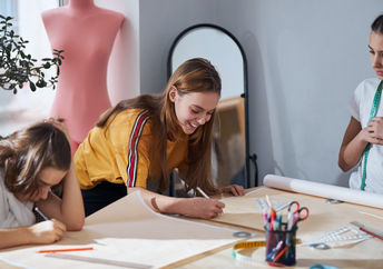 Cute girls drafting sewing patterns for dressmaking.