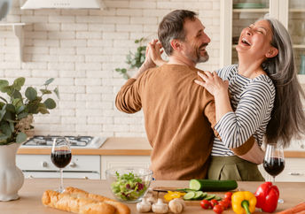Happy couple dancing together in the kitchen while cooking.