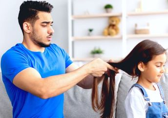 A young father making a braid for his little daughter.