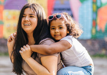 A mother carries her daughter.
