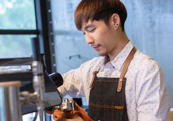 Barista at work cleaning equipment in a café.
