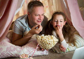 Father and daughter enjoying a dog-themed movie together.