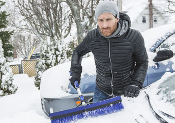 Man cleaning off neighbor's snowbound car,
