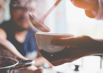 A woman warms up with a hearty soup.