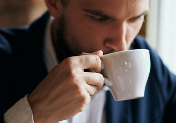 Portrait of a man enjoying a warm beverage in a porcelain cup.