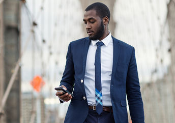 Young businessman using mobile phone on Brooklyn Bridge, New York City.