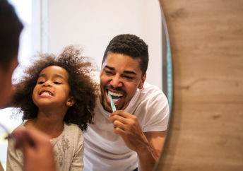 A woman looks in the mirror as she brushes her teeth.