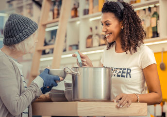 A volunteer giving soup to the homeless.