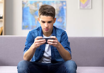 A teenager playing a game on his phone.