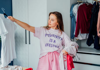 Woman cleaning out unwanted clothing from her closet.
