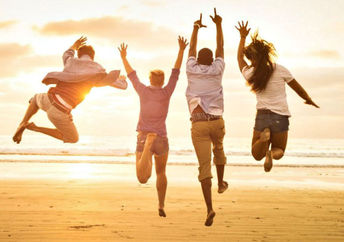 A group of friends jump for joy on the beach.