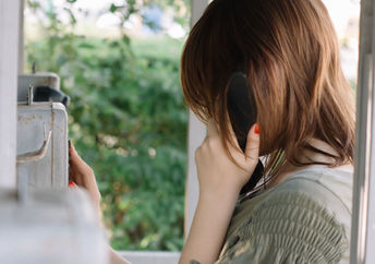 Young woman talking on a phone surrounded by flowers.