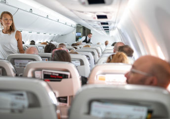 Young woman aboard an airplane walking in the aisle