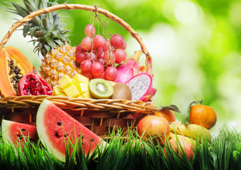 Basket of tropical fruits on green grass.