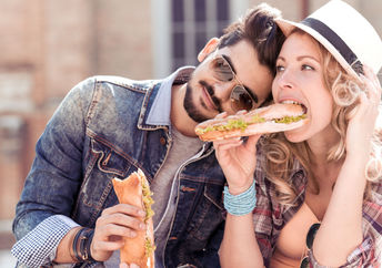 Couple enjoying a sandwich lunch outside.