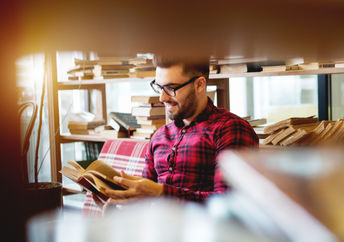 Young man reading a book at a modern library.