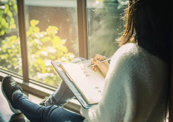 Woman writing her thoughts down in a journal.