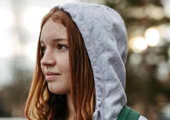 Gen Z young woman wearing a hoodie outdoors.