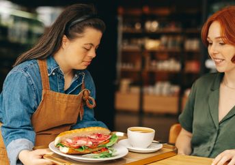 Waitress with down's syndrome serving a customer.