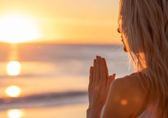 Girl meditating at sunset on beach