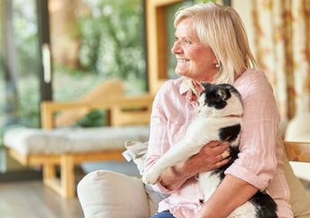 Senior woman cuddling a pet cat.