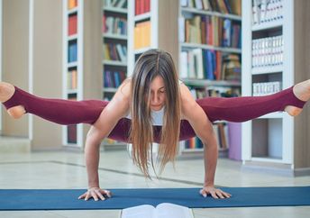 Young woman reading and practicing yoga in the library.