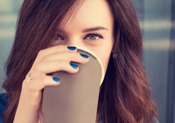 Smiling woman drinking coffee from a paper cup.