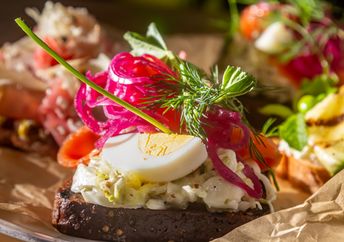 A traditional Danish sandwich with salmon, egg, and salad on rye bread.