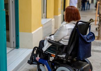 Woman cannot access a store that does not have a wheelchair ramp.