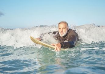 a senior man bodyboarding in the surf.