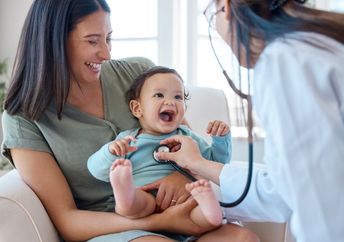 A baby smiles during a medical checkup.