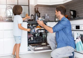 Father and son load a dishwasher.