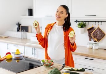 A pregnant woman eating a healthy salad with avocado.