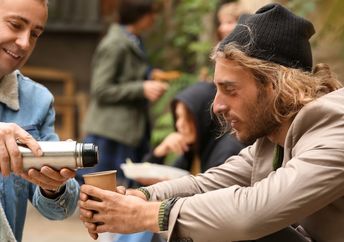 Giving a person on the street a hot drink on a cold morning.