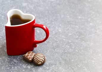 A mug on a table with chocolates next to it.