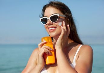 A woman puts on sunscreen on a sunny day.