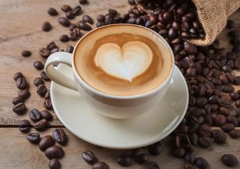 Cup of coffee latte with heart shape and coffee beans.