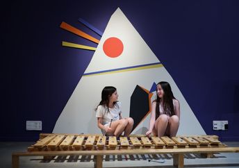 Two girls play with an instrument.