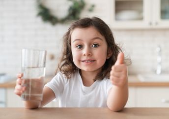 A cute girl enjoying a glass of fresh water.