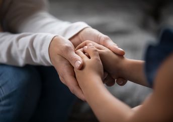 An adult and a child hold hands.