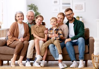 A family smiles while sitting on a couch.